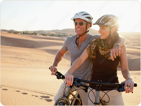 Couple pausing mid-ride on their bikes in the dunes